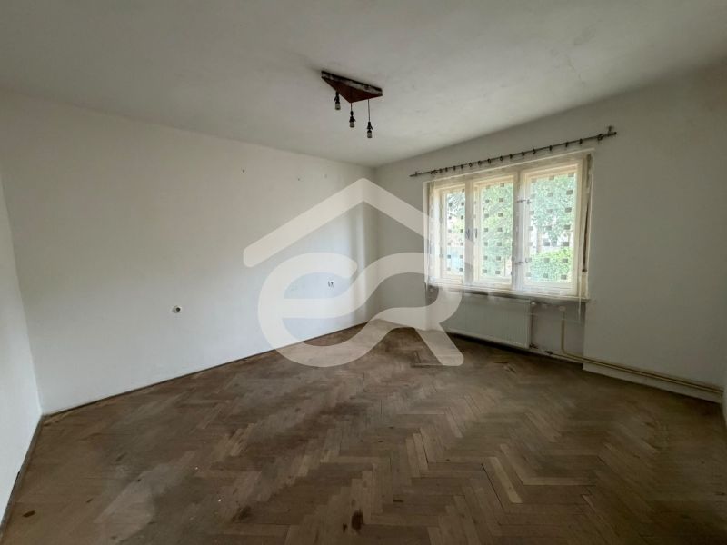 An empty room with a wood-patterned floor and a large window in a family house.
