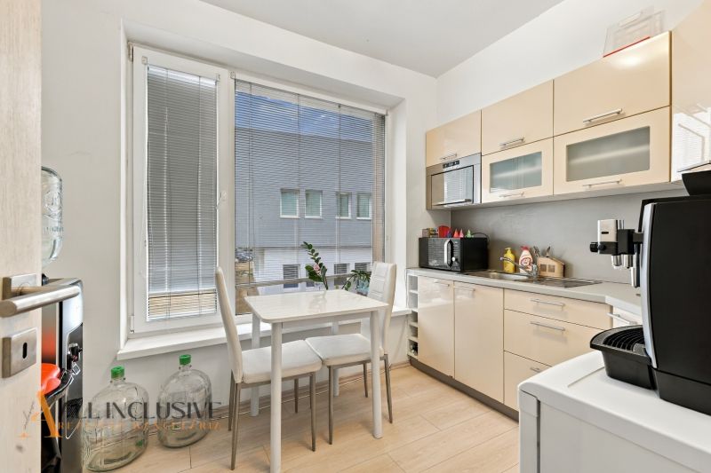 Office kitchenette with a dining table, large window, and wood-patterned floor.
