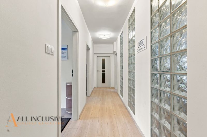 A narrow hallway in offices with a wooden decor floor and a glass wall.