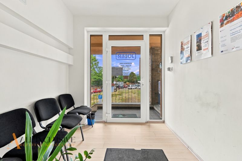 Entrance to offices with wood-patterned flooring, waiting area, and posters on the wall.