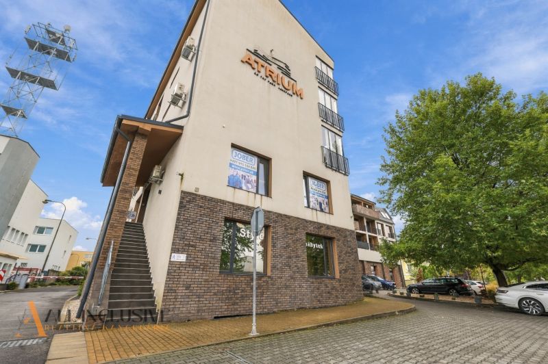 A building with a sign in Dunajská Streda. A parking lot and a tree surround the offices.