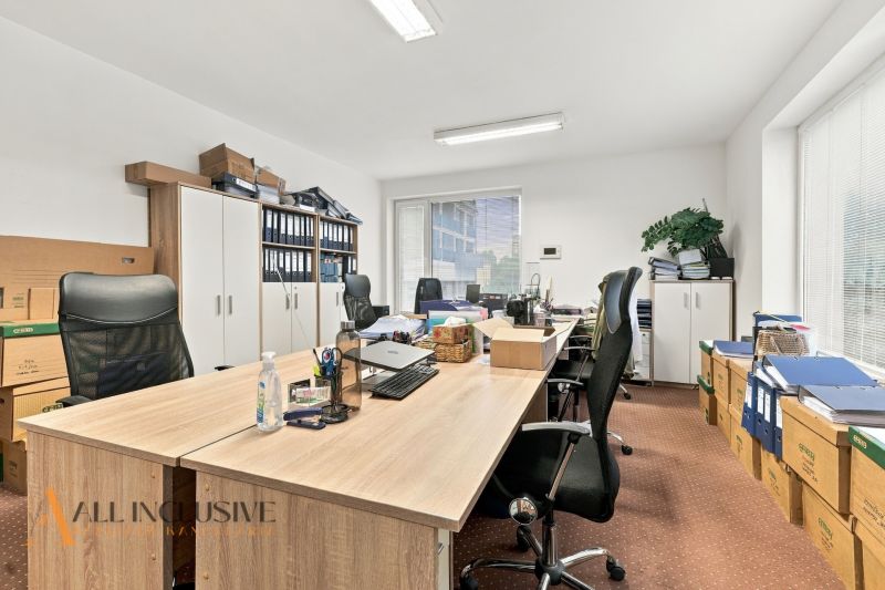 Offices with wood-patterned flooring, desks, chairs, and boxes full of documents.