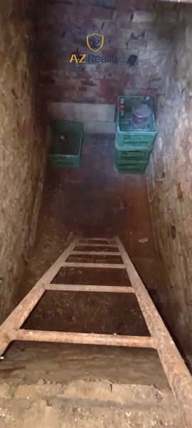 A narrow staircase with a ladder leads to the basement in the Gardens with brick walls.