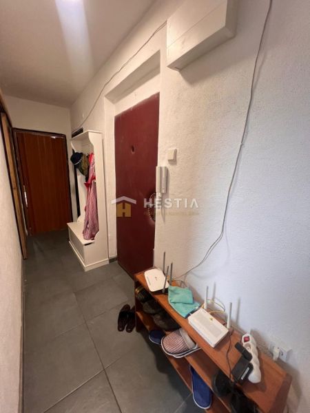 A hallway in a 3-room apartment with a shelf and a coat rack.