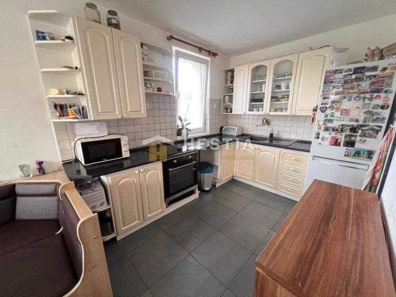 A kitchen with a corner unit, white cabinets, and a black countertop in a three-room apartment.