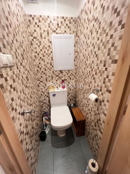 A toilet with mosaic tiles in a 3-room apartment, flooring, enclosed space.