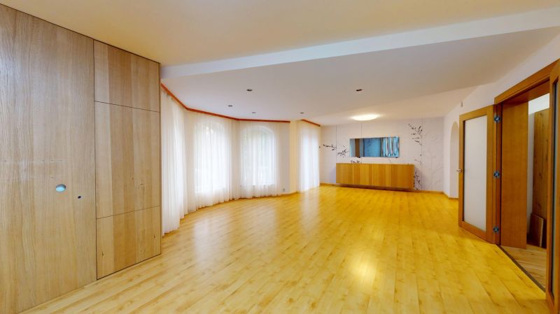 A spacious living room with wood-patterned flooring and large windows.
