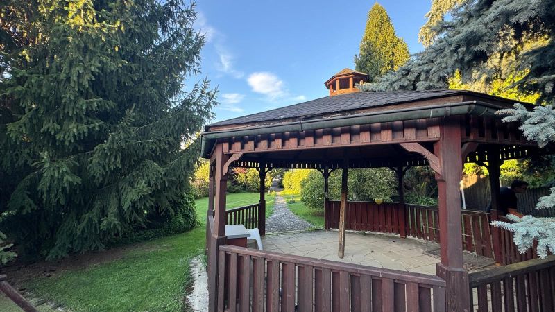A garden gazebo by a family house in Trenčianske Stankovce surrounded by coniferous trees.