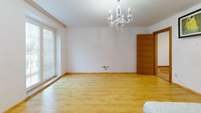 Interior of a family house with a chandelier, balcony doors, and a wooden decor floor.