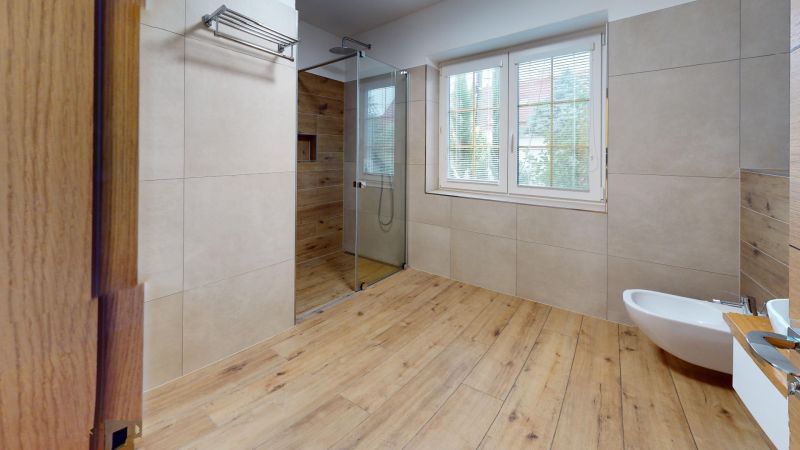 A bathroom in a family house with a wooden decor floor and a shower corner.