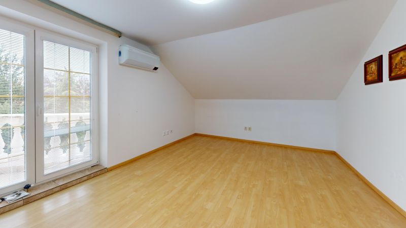 Attic room in a family house with a wooden decor floor and air conditioning.