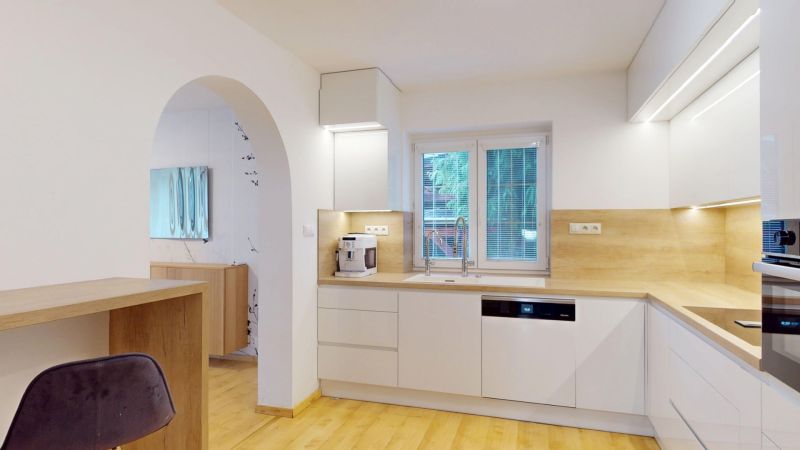 A kitchen in a family house with white cabinets, appliances, and a wooden decor floor.