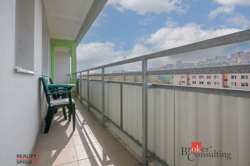 A balcony with plastic furniture and a view of apartment buildings in Bratislava-Karlova Ves on Donnerova.