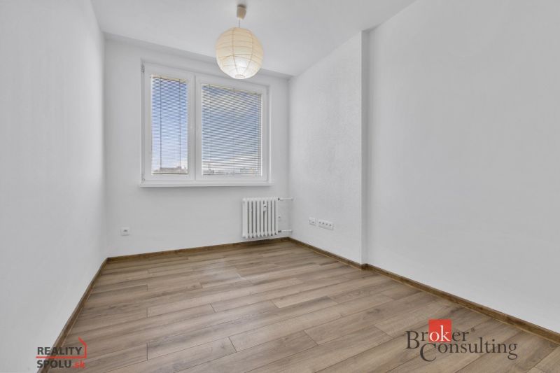 A bright room with wood-patterned flooring, a window, and a radiator in a 5+ room apartment.