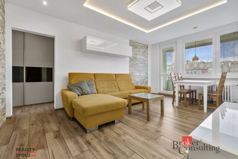 A living room in a 5 or more room apartment with a wood-patterned floor and a yellow sofa.