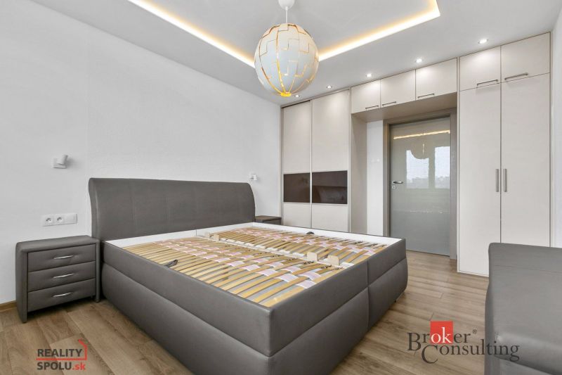 A bedroom with wood-patterned flooring, a built-in wardrobe, and lighting in a five or more room apartment.