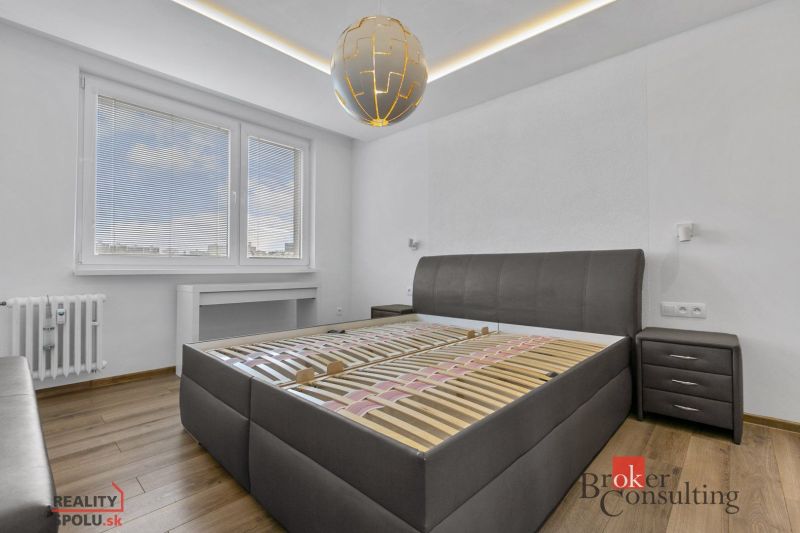 A bedroom in a 5 or more room apartment with a bed, furniture, and flooring with a wood decor.