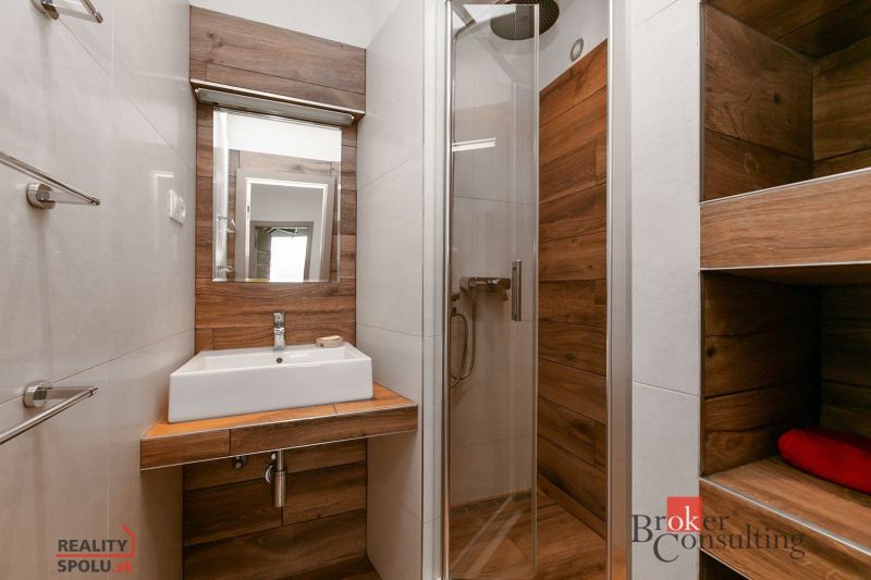 A bathroom in a 5 or more room apartment with a sink and shower, tiles with a wooden decor.