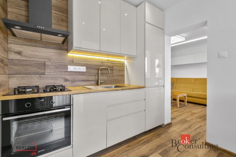 A kitchen in a 5 or more room apartment with a wooden decor floor and a light kitchen unit.