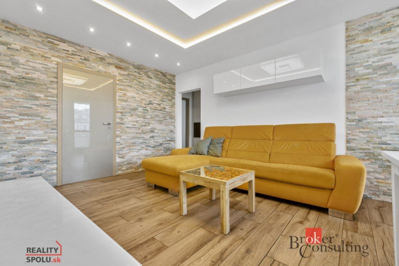 A living room with a wood-patterned floor and a yellow sofa in a 5 or more room apartment.