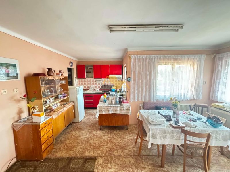 Dining room and kitchen in a family house with a red kitchen unit and a glass cabinet.