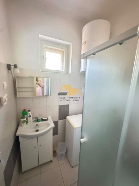 Bathroom in a family house with a sink, shower, and washing machine.