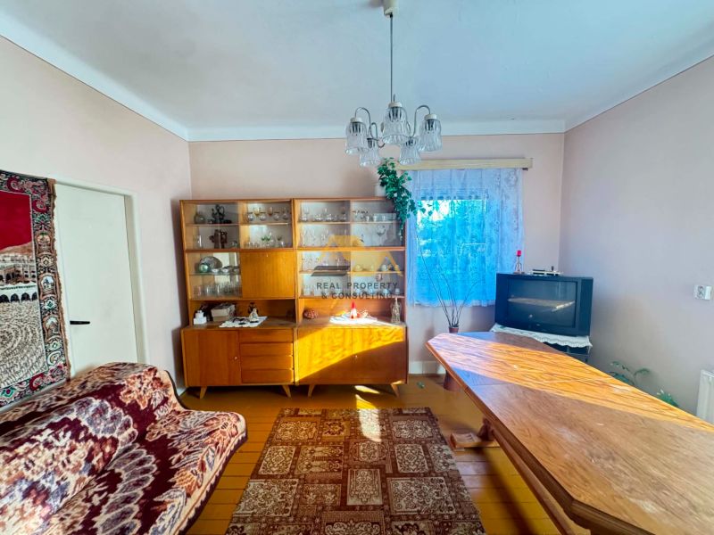 A living room in a family house with a wooden decor floor, carpets, and a television.