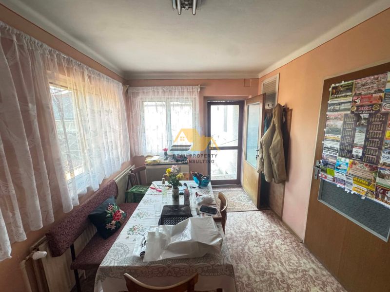 A dining room in a family house with a long table and flowers on it.