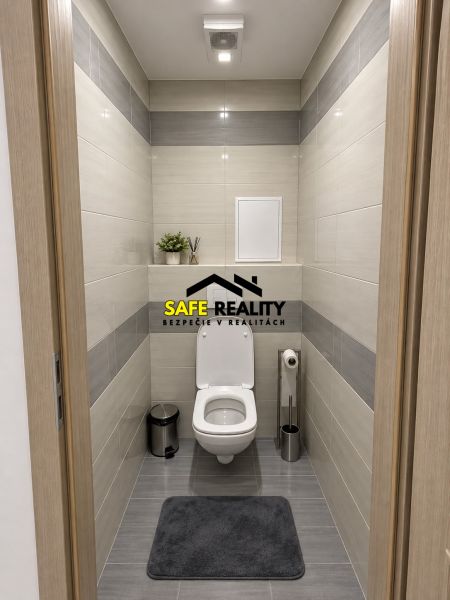 Bathroom in a 3-room apartment with a white toilet and gray tiles.