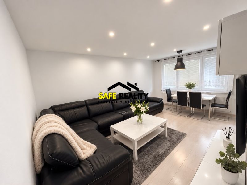 Living room of a 3-room apartment with a leather sofa, dining table, and wooden decor flooring.