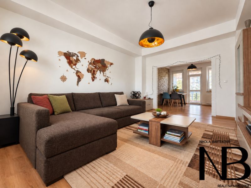 Living room with a sofa, a world map on the wall, and a floor with a wooden decor.