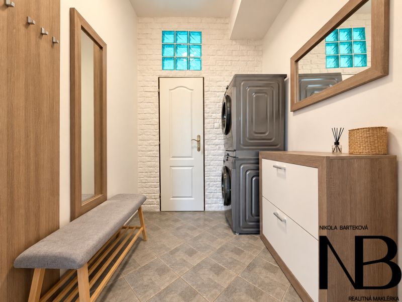 A hallway with a mirror, a washing machine, and a dryer in a 3-room apartment with a wooden decor floor.