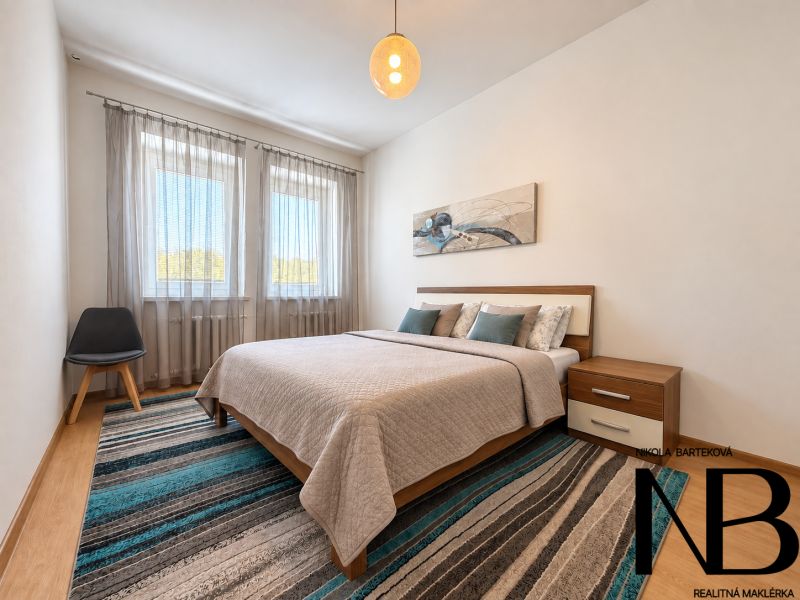 A bedroom in a 3-room apartment with a bed, an armchair, and a floor with a wooden decor.