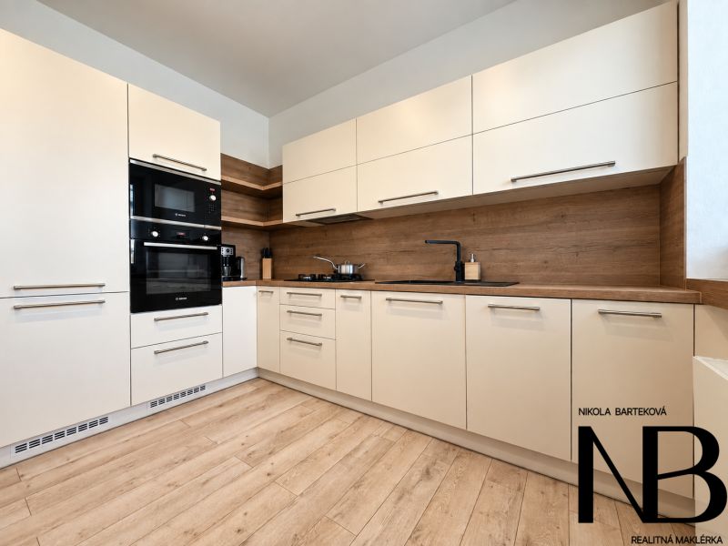A kitchen in a 3-room apartment with light cabinets and a wood-patterned floor.