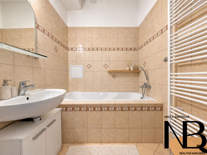 A bathroom in a 3-room apartment with a bathtub, sink, and tiles in soft tones.