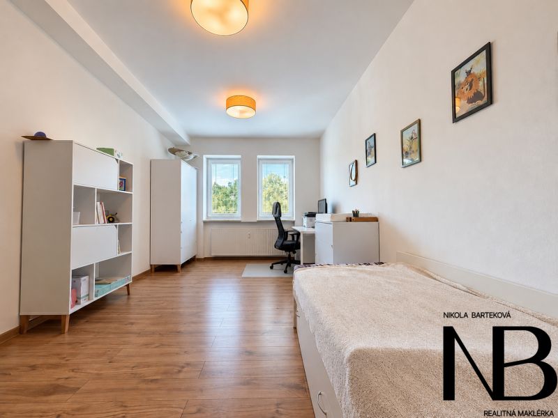 A bright room in a 3-room apartment with a wood-patterned floor, one bed, and an office desk.