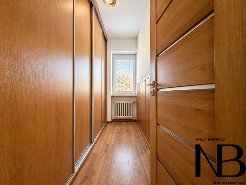 A hallway with a built-in wardrobe and a floor with a wooden decor in a 3-room apartment.