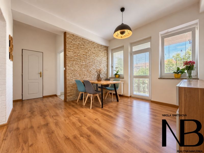 Living room in a three-room apartment with a wooden decor floor and a dining area.