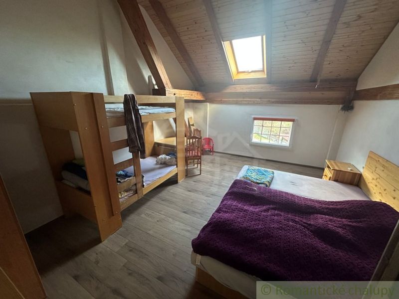 Attic room with a bunk bed, a double bed, and a floor with wooden decor.