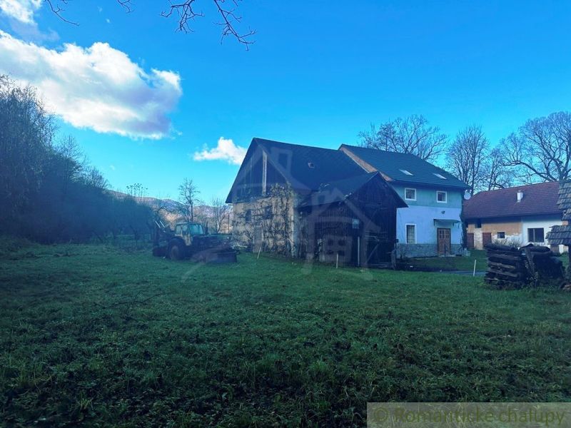 A family house in Mokrá Lúka with a tractor on a spacious garden surrounded by nature.