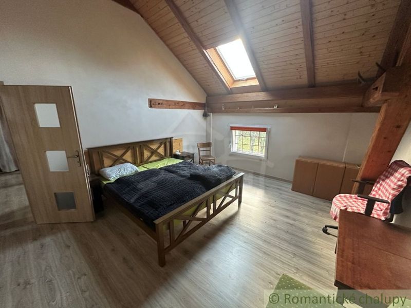 Attic bedroom in a family house with a bed and wooden decor flooring.