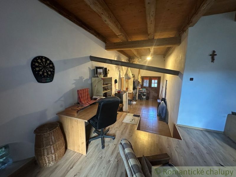 Attic office in a family house with a wooden decor floor and a wooden ceiling.