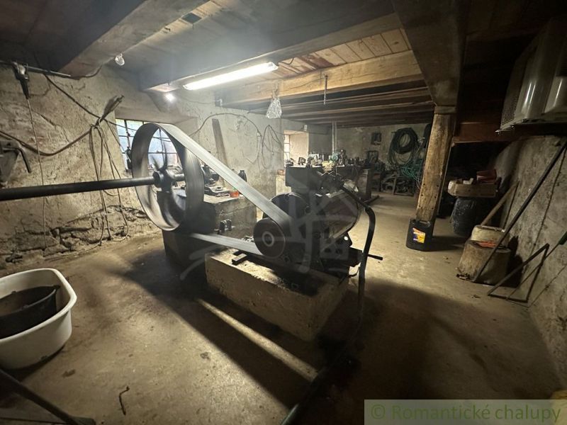 Windows, machines, and tools in the basement of a family house with stone walls.