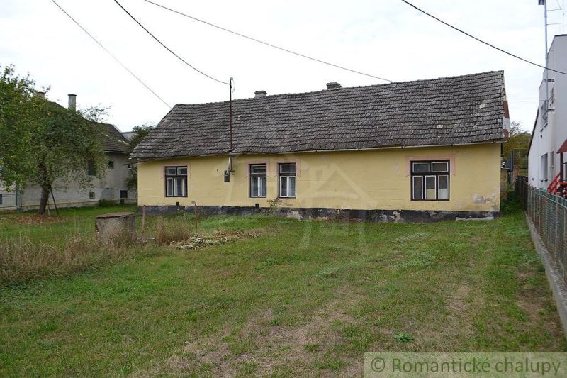 A family house in Nemcovce with a worn-out roof and yellow facade, surrounded by a lawn.
