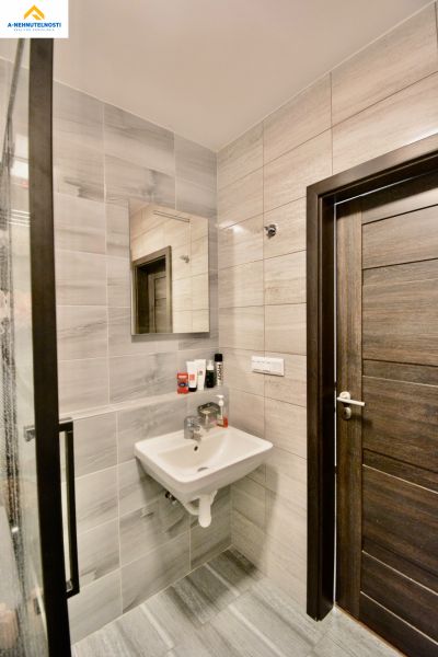 A bathroom with a sink and a mirror in a 3-room apartment, tiles in shades of gray.