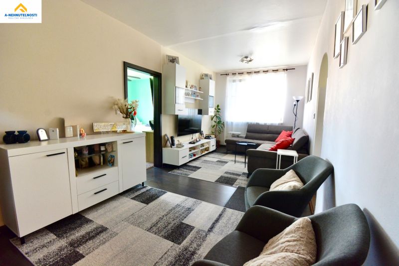 Living room in a 3-room apartment with a sofa, TV cabinet, and armchairs on a floor with a wooden decor.