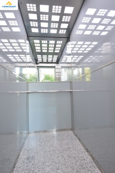 An elevator with reflective panels and a patterned ceiling in a building.