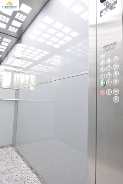 Interior of an elevator with a lit ceiling and a panel with buttons for a 3-bedroom apartment.