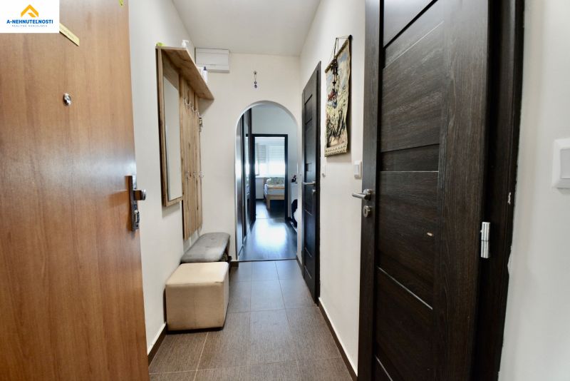 A hallway with dark doors and furniture in a 3-room apartment with a wooden decor floor.