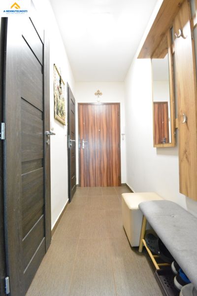 A hallway in a 3-room apartment with tiles, dark doors, and wall decorations.